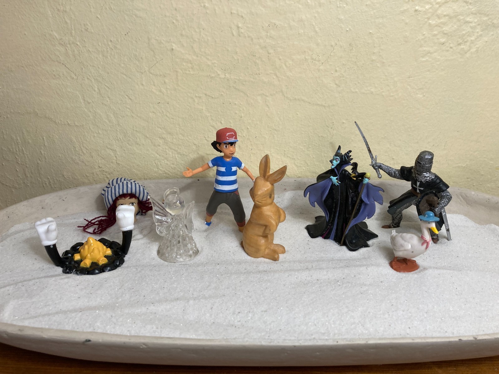Dozen sand tray figure miniatures address ideas of childhood, danger, and safety