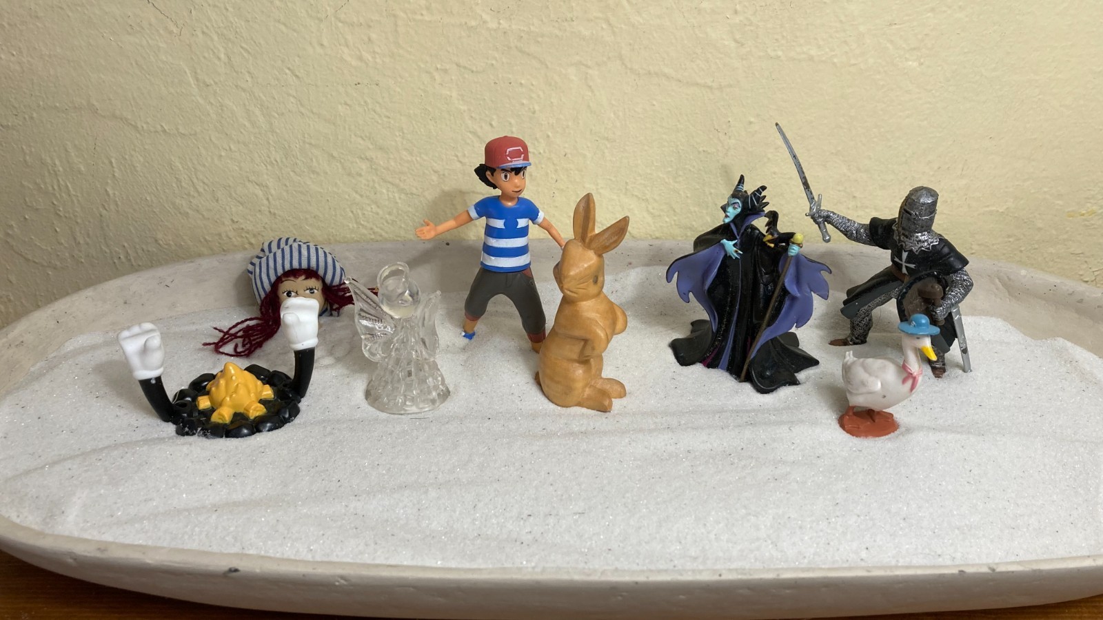 Dozen sand tray figure miniatures address ideas of childhood, danger, and safety